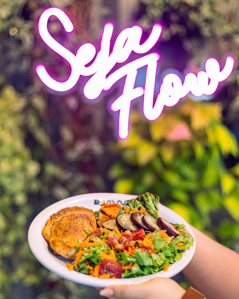 Letreiro neon “Seja Flow” e prato servido na mão