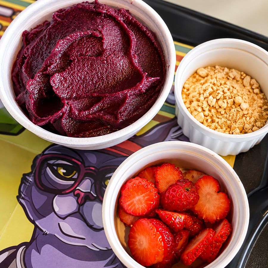 Açaí servido com morangos e complemento crocante