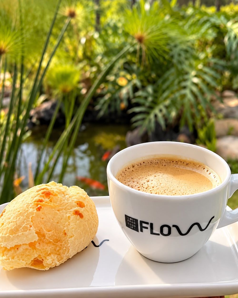 Café e pão de queijo em xícara Flow, com jardim ao fundo